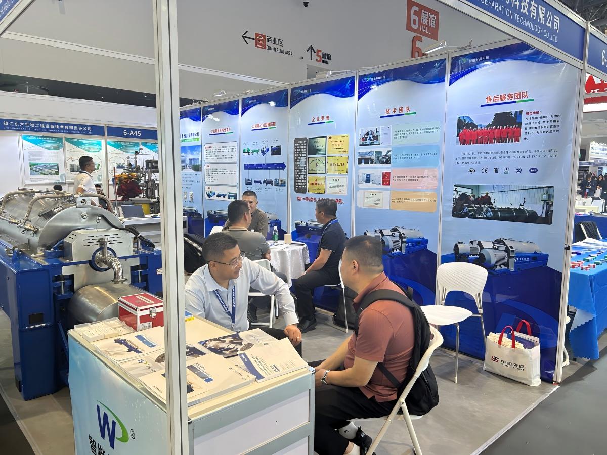 A visitor reviewing ZK SEPARATION pharmaceutical centrifuge materials at the booth counter